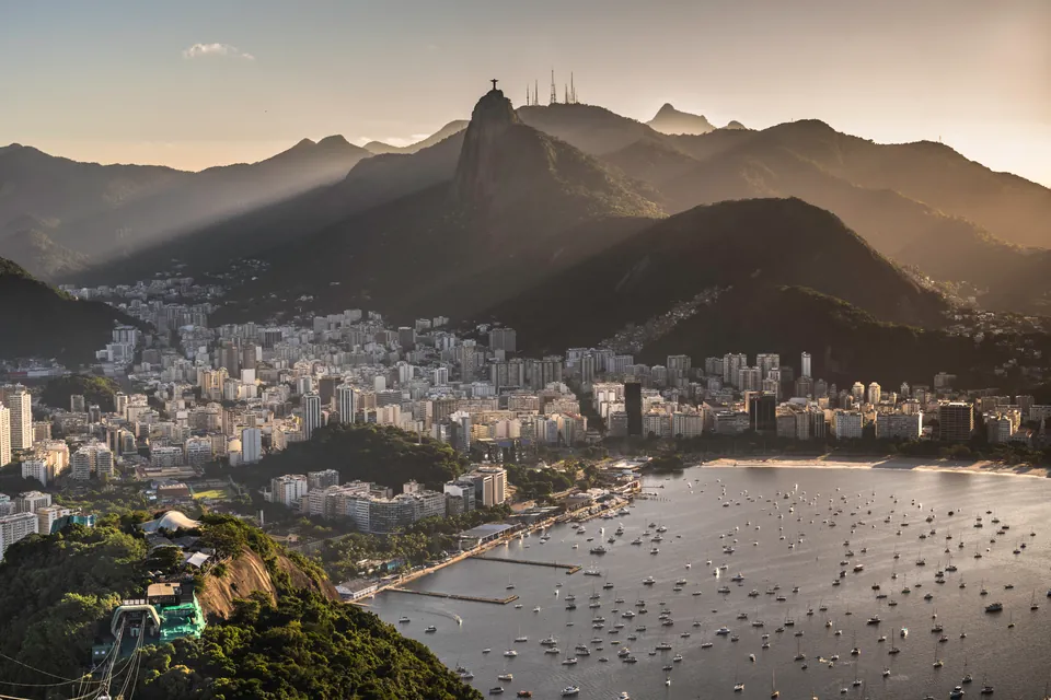 Rio de Janeiro at golden hour: mountains in haze, the city along the bay, and boats moored in the water below
